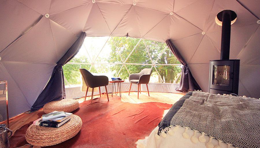 interior of geodesic dome with view at window, coffee table, chairs and fireplace