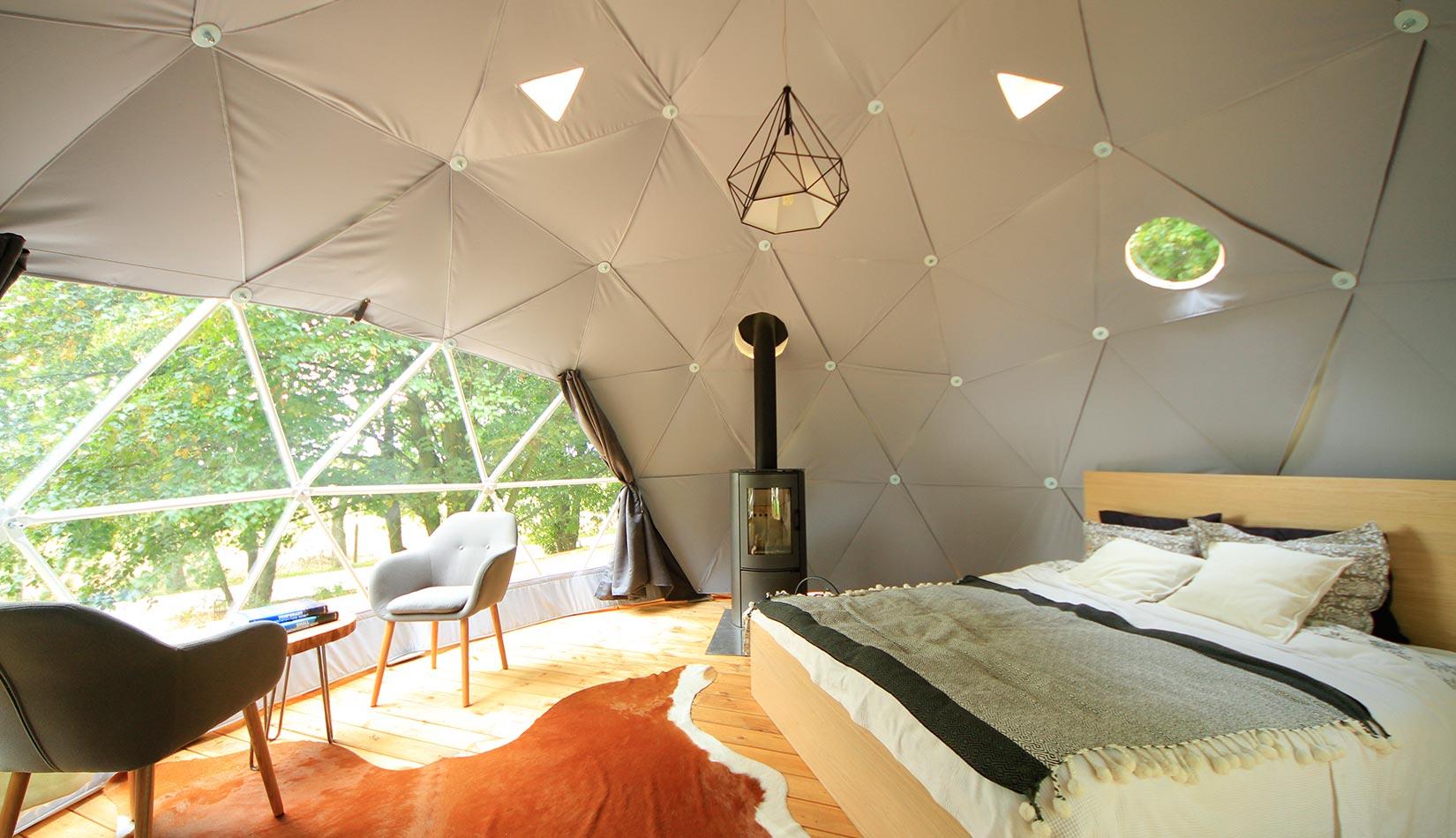 interior of geodesic dome with view at window, chairs, table coffee and fireplace