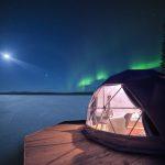 white geodesic dome on a wooden platform with a view of the aurora borealis