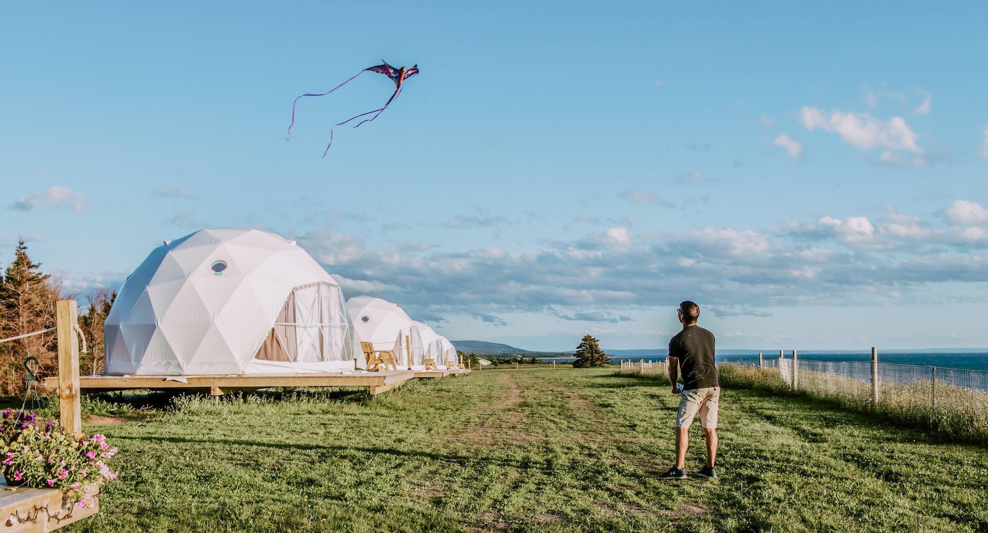 a man with fly a kite against the background of geodesic domes located near the cliff