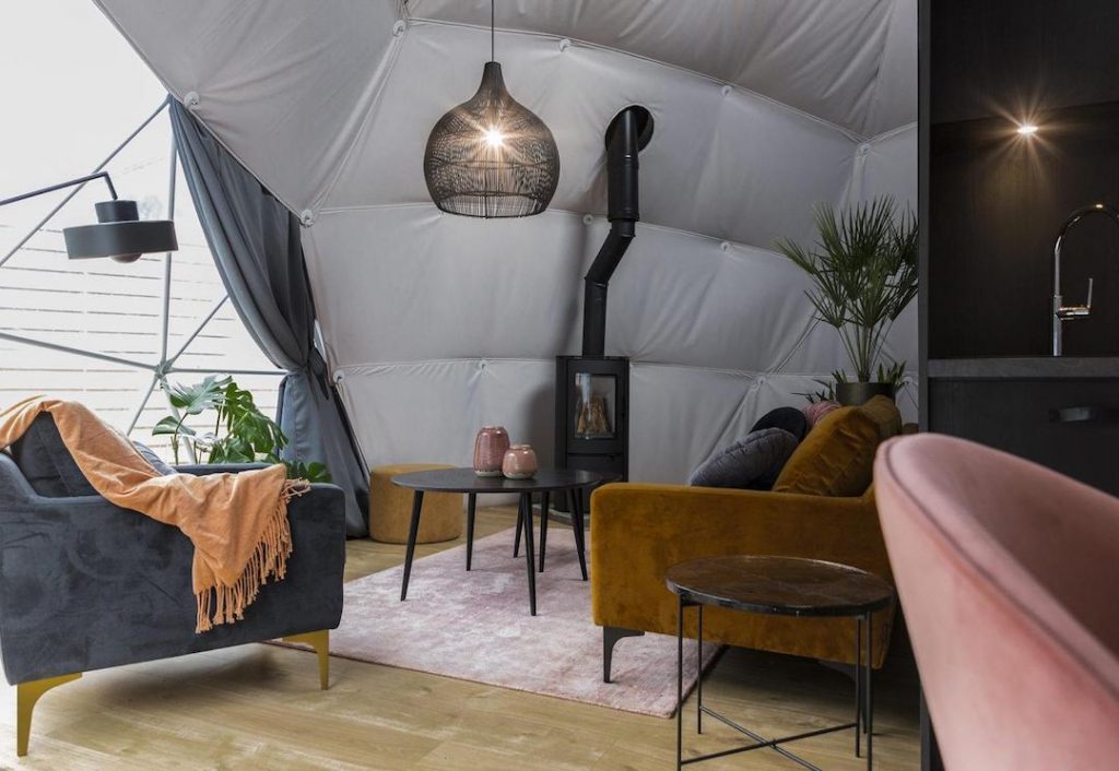 interior of geodesic dome with view at black module, coffee table, sofa, chairs and fireplace