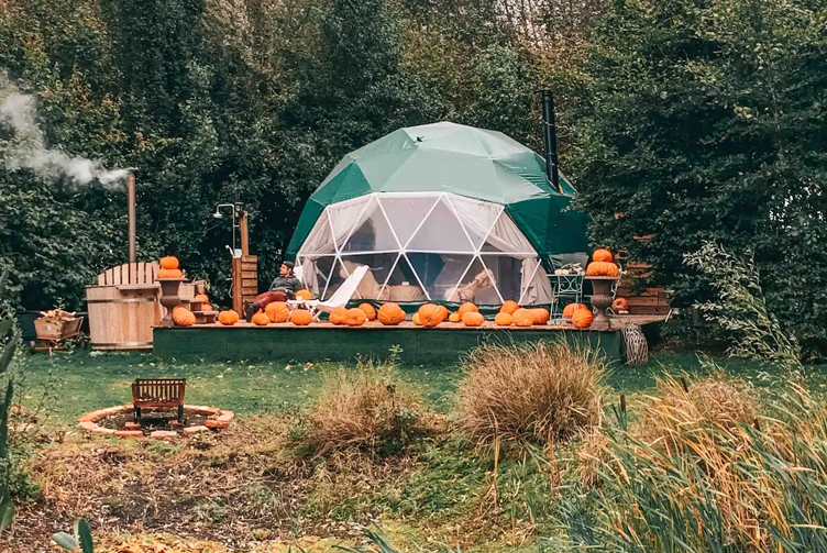 green geodesic dome with stack on wooden platform with autumn accessories