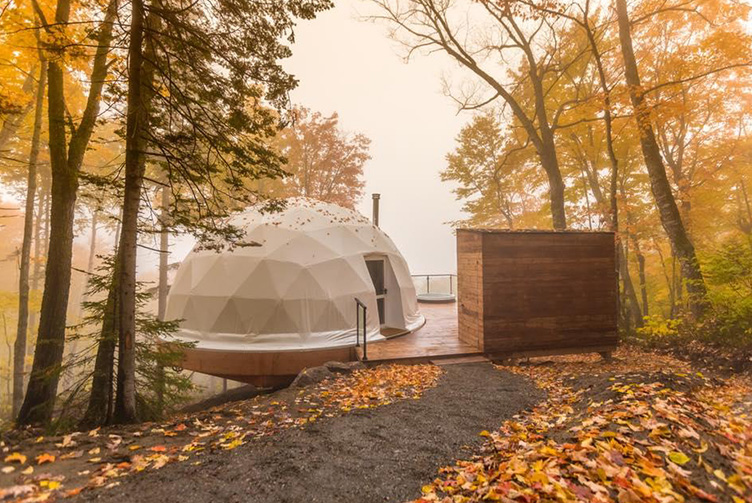 white geodesic dome on wooden platform in forest in autumn