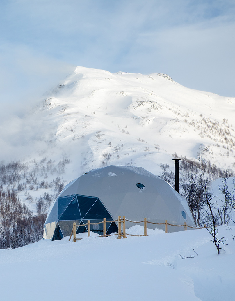 white geodesic dome with stack in snow in mountain