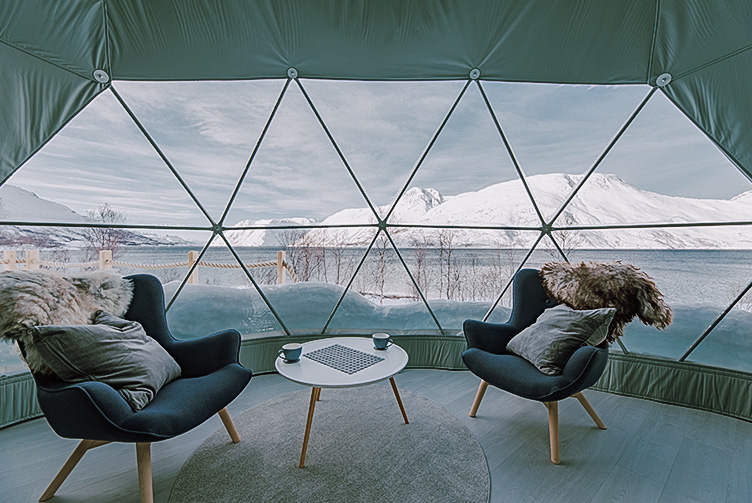 interior of geodesic dome with view at window, coffee table and chairs, in the background winter