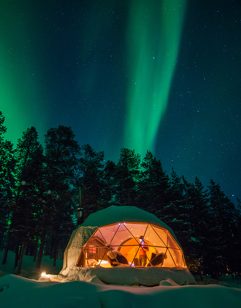 white geodesic dome in the snowy forest against the backdrop of the aurora borealis