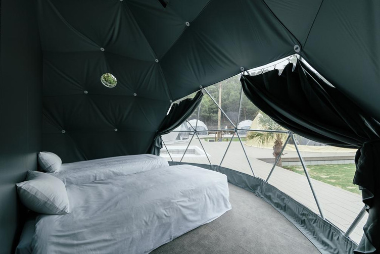 inside of the glamping geodesic dome with dark grey insulation with two single beds and dark color curtains