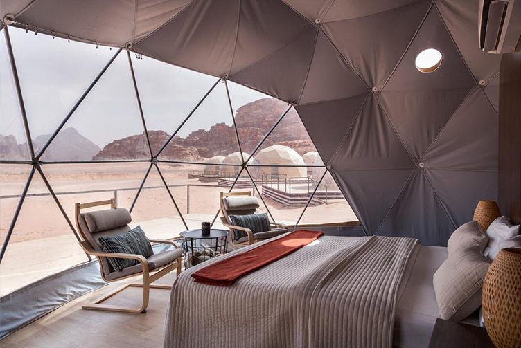 interior of geodesic dome with view at window, coffee table, chairs and insulation, desert in the background