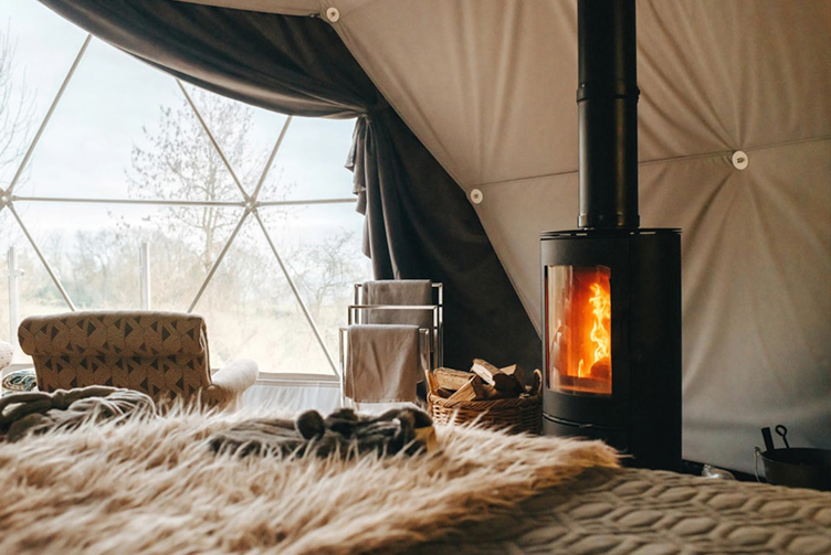 interior of geodesic dome with view at fireplace, bed and window