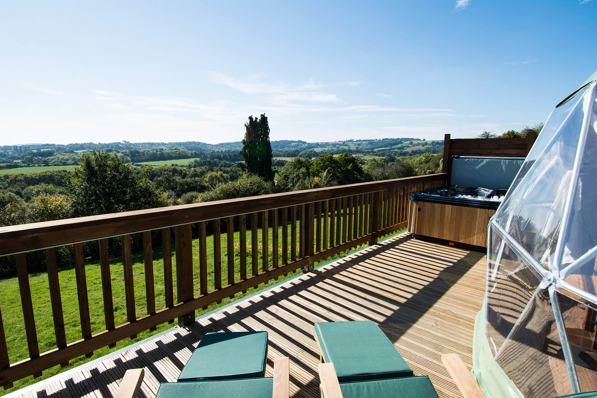 green geodesic dome on a wooden platform overlooking nature