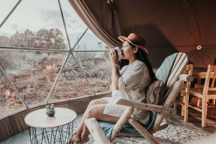 woman on a chair drinking coffee inside a geodesic dome