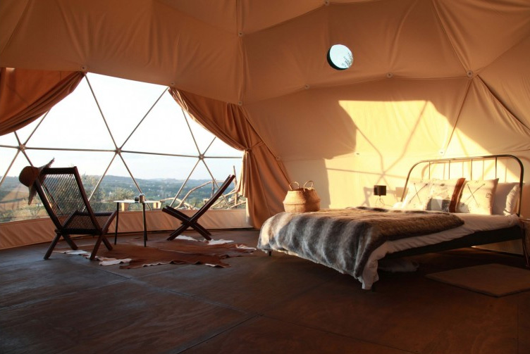 interior of geodesic dome with view of chairs, bed and window during sunset