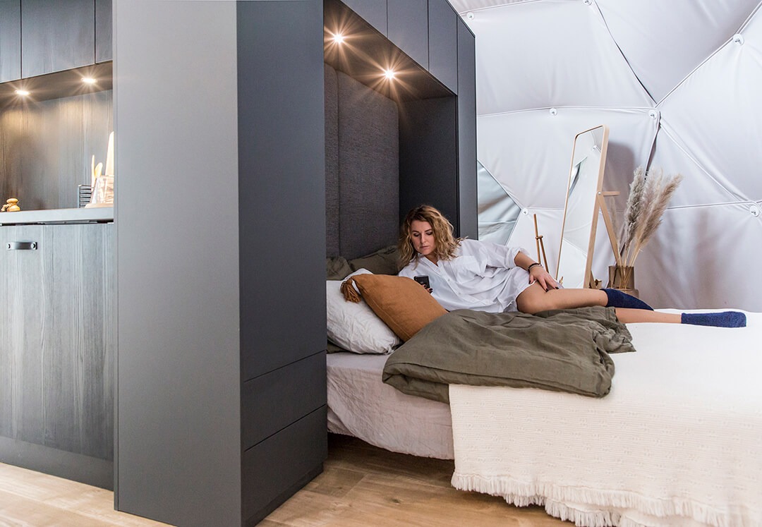 Bedroom Module with blanket and a woman on the bed, spacious and modern interior with mirror in the background