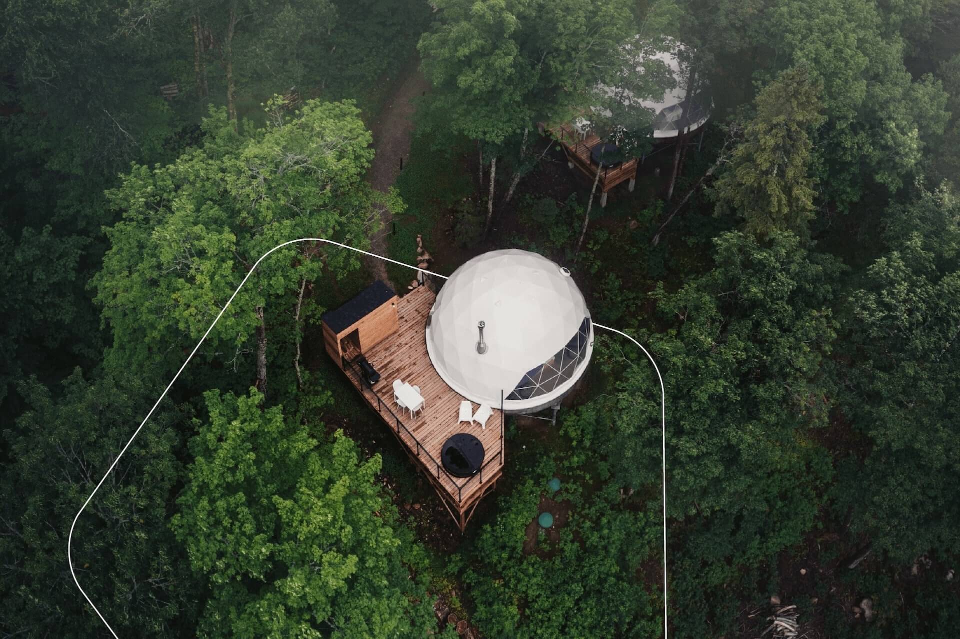 white geodesic dome in the forest on wooden deck