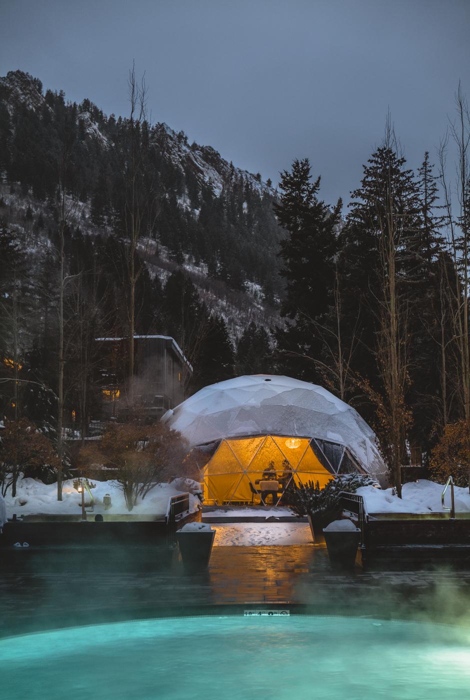 a white geodesic dome in winter, In the foreground, the illuminated swimming pool