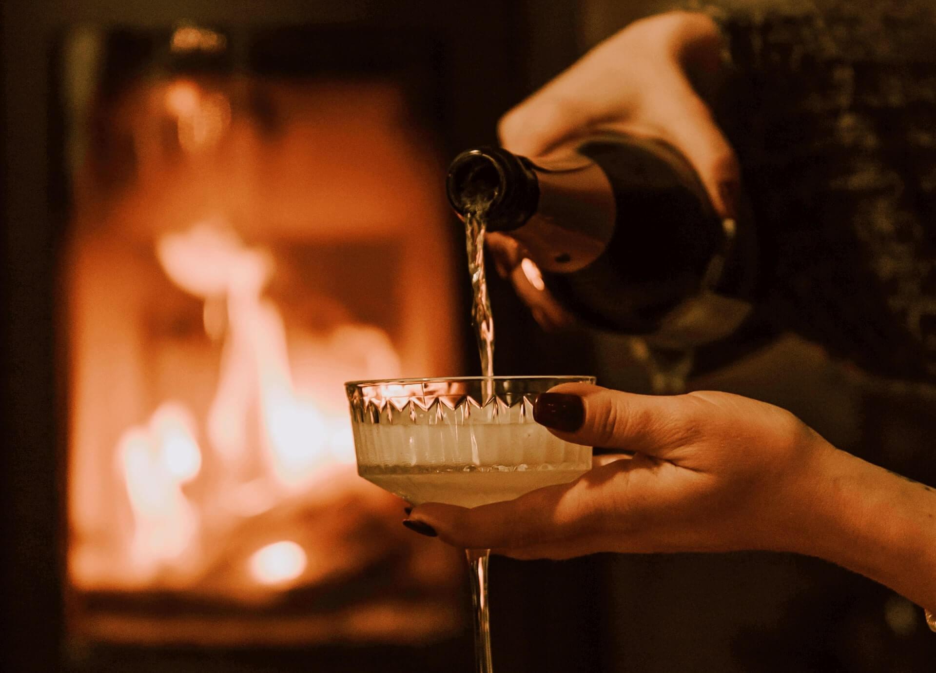 champagne glass, champagne with a fireplace in the background