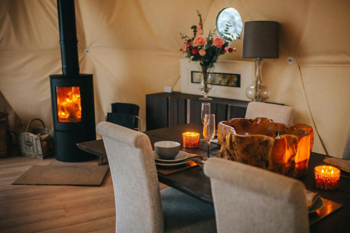 FDomes Glamping interior arranged dining area with wood-burning stove in the back