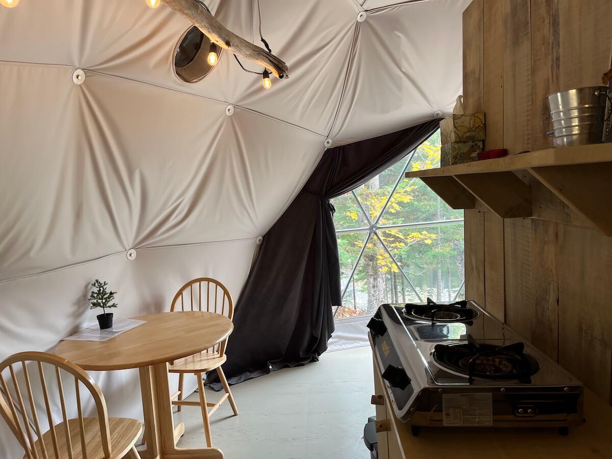 inside of geodesic dome with two chairs, a table, a window and camp kitchen