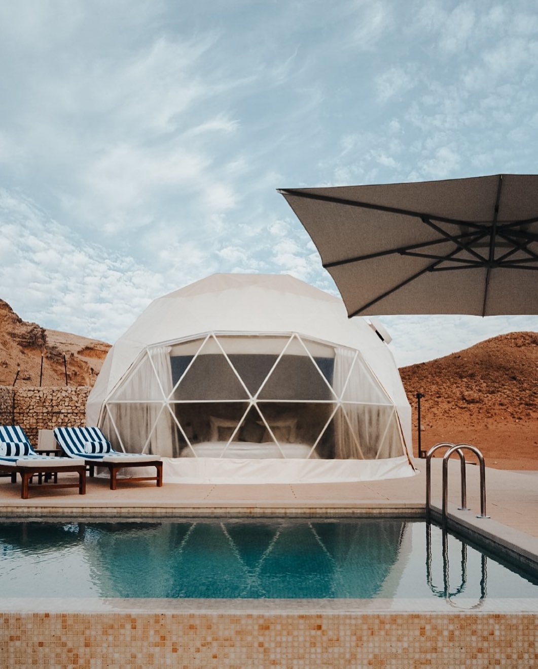 luxury white geodesic dome with a private pool and armchairs on the campsite