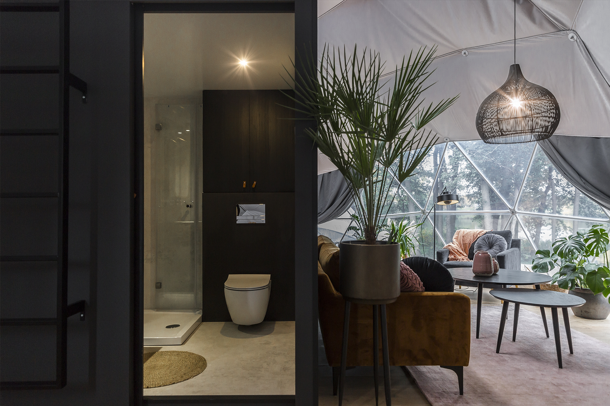 inside of geodesic dome with interior module bathroom, a sofa, an armchair and two tables