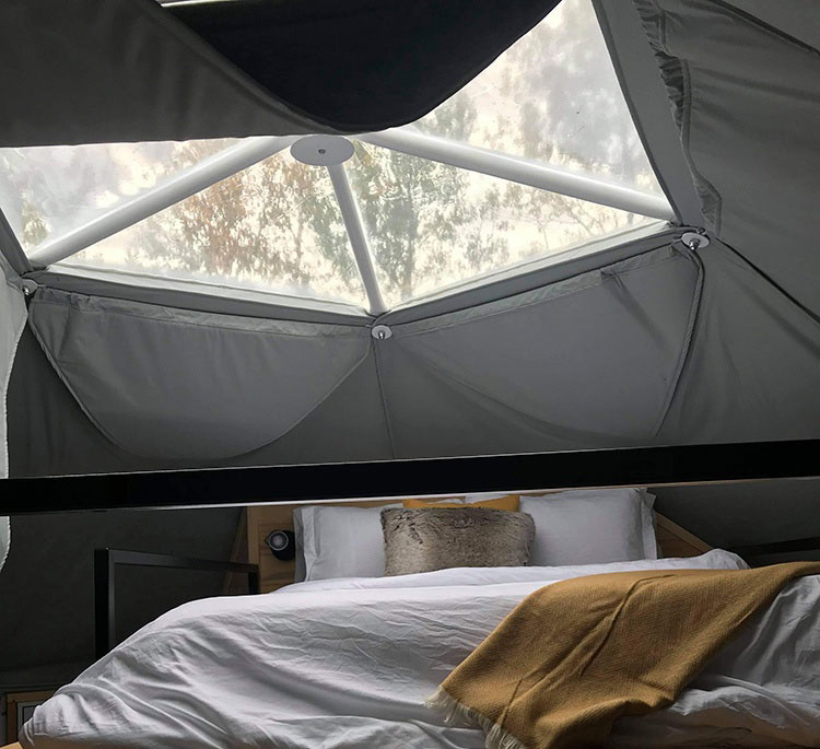 inside of geodesic dome with loft bed on mezzanine and a skylight