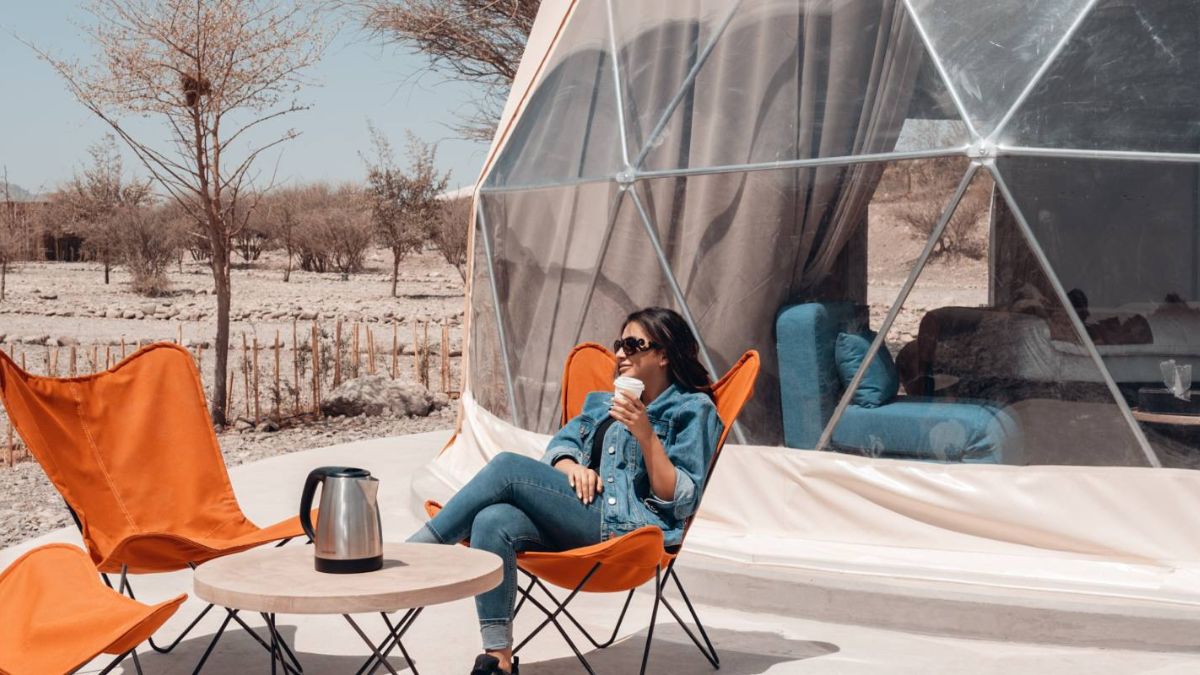 woman sitting in front of white geodesic dome on the desert