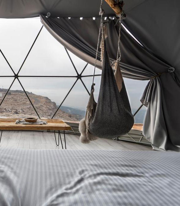 inside of geodesic dome with a bed, a table and a window