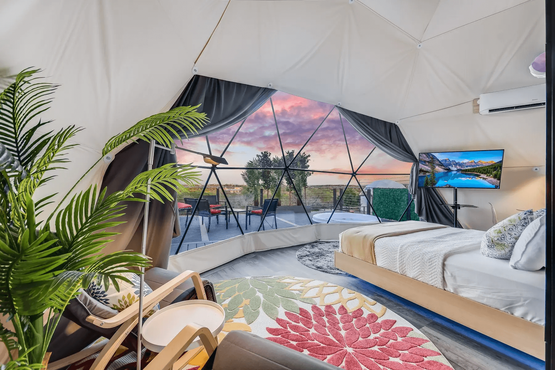 inside of geodesic dome with a bed, a tv, a carpet and a window