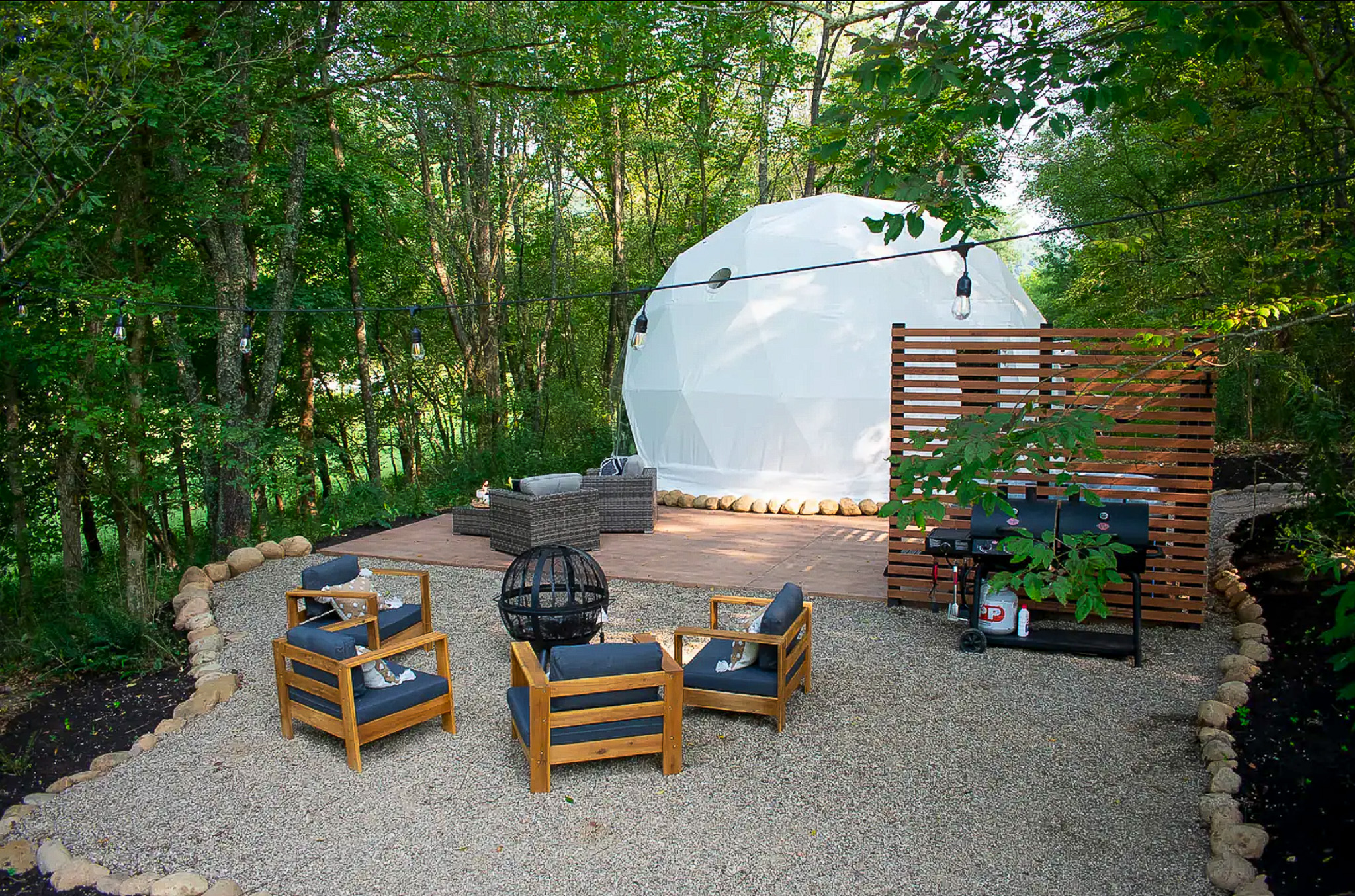 white geodesic dome with some chairs and ta table in a forest