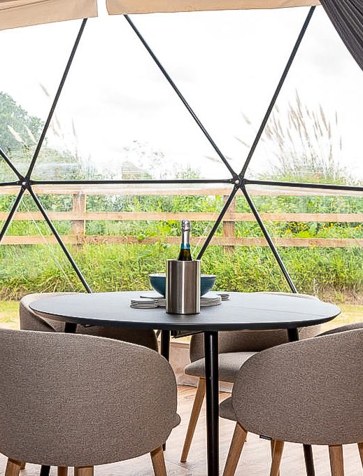 inside of geodesic dome with two chairs and table and a view on garden through window