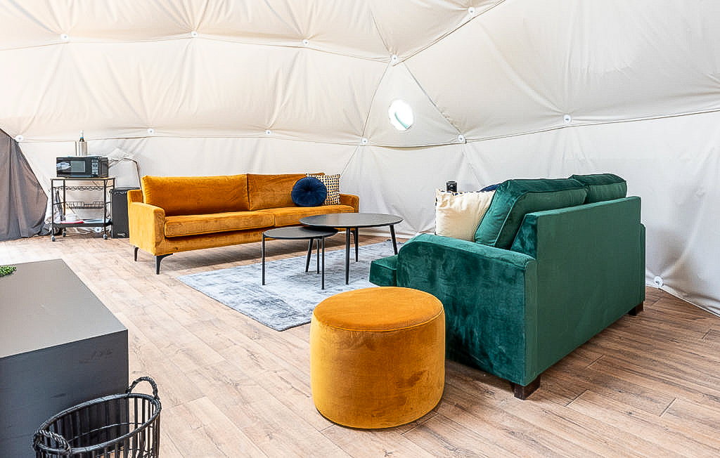 inside of geodesic dome with two sofas, two tables and a carpet
