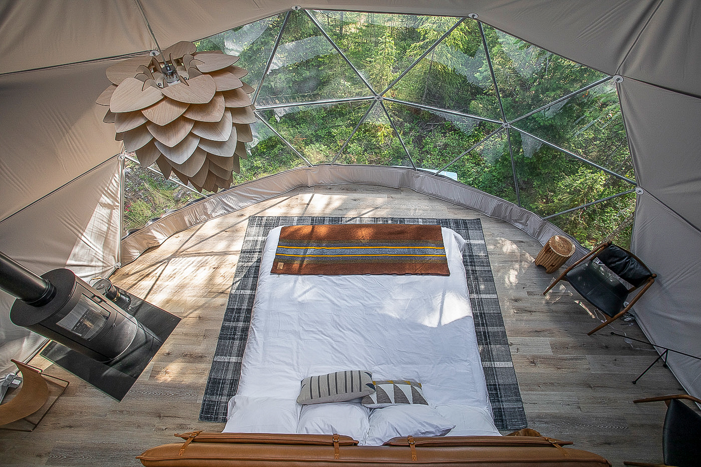 inside of the geodesic with a bed, a stove and an armchair