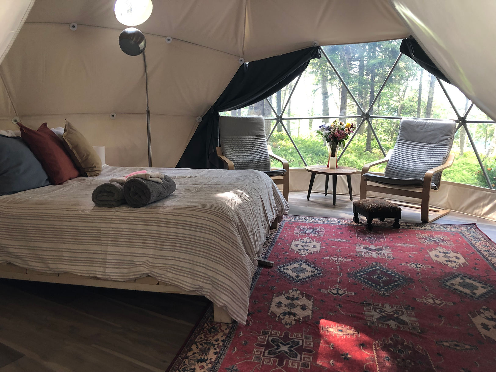 inside of geodesic dome with two armchairs and a bed