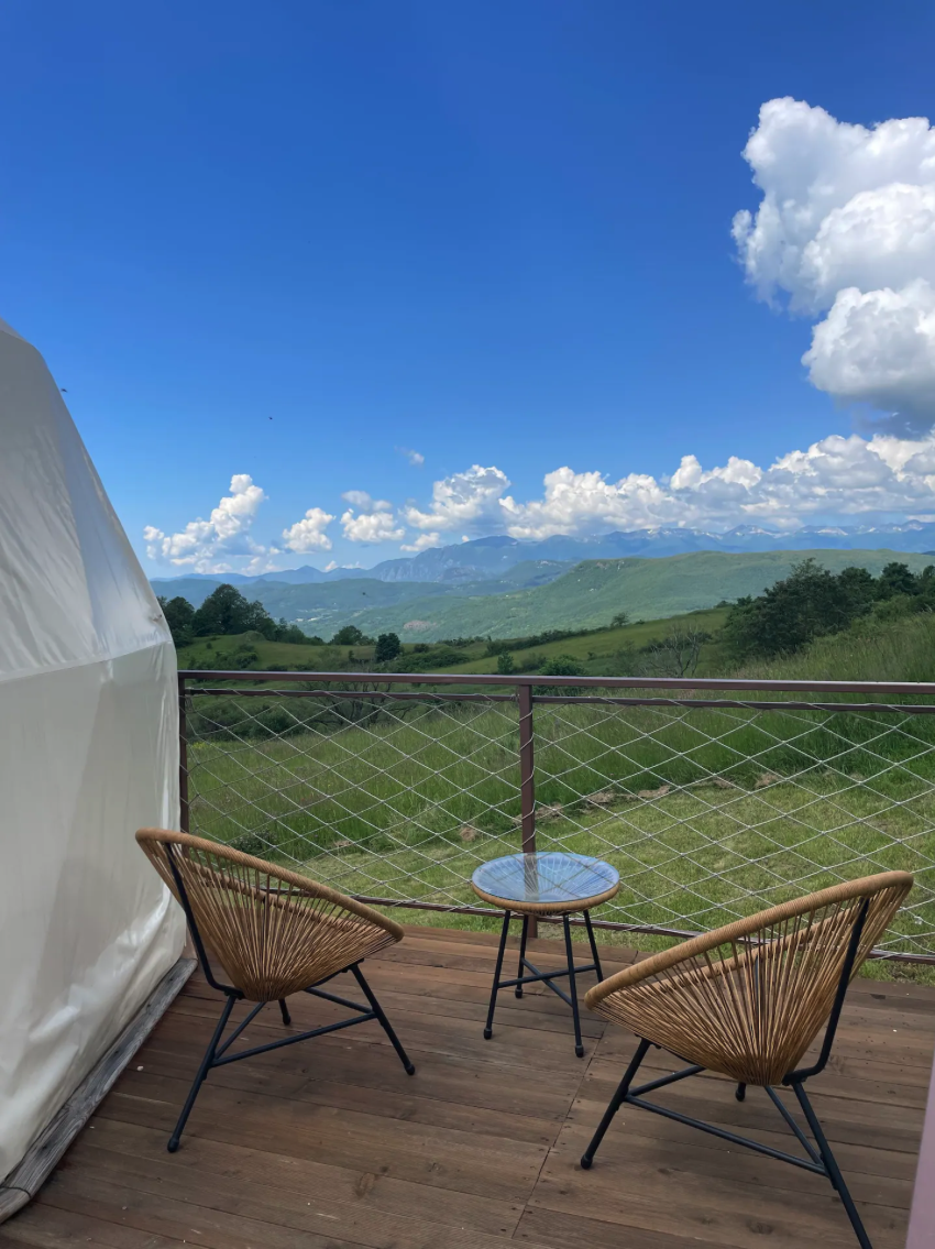 terrace near white geodesic dome with a view of mountains and fields