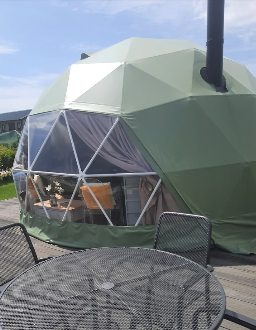 green geodesic dome on wooden deck with a table and some chairs