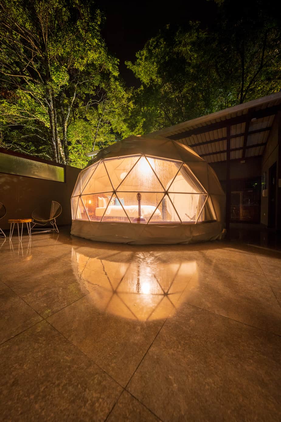 white geodesic dome on a wooden platform surrounded by nature at night